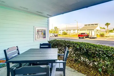 a picnic table and chairs on the side of a house at Walkable Panama City Beach Condo with Pool Access! in Panama City Beach