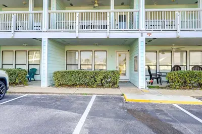 a building with a balcony and a parking lot at Walkable Panama City Beach Condo with Pool Access! in Panama City Beach