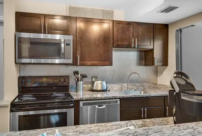 a kitchen with stainless steel appliances and wooden cabinets at Horizon South 8B2- Sunshine Gardens in Panama City Beach