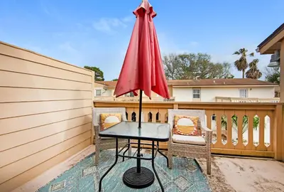 a patio with a table and chairs and an umbrella at Horizon South 8B2- Sunshine Gardens in Panama City Beach