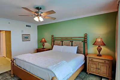 a bedroom with a bed with a ceiling fan and two lamps at Palazzo #1407 in Panama City Beach