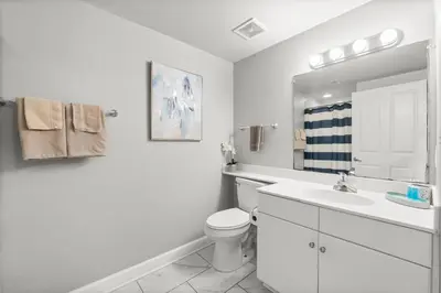 a white bathroom with a toilet and a sink at Modern Beachfront Condo on the Beach Sleeps 6! by Dolce Vita Getaways PCB in Panama City Beach