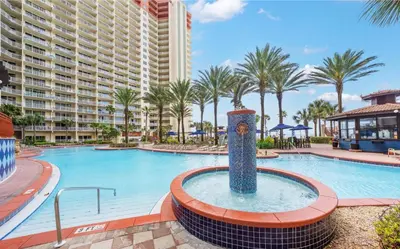 a pool at a resort with palm trees and a large building at Modern Beachfront Condo on the Beach Sleeps 6! by Dolce Vita Getaways PCB in Panama City Beach