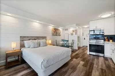 a bedroom with a white bed and a kitchen at Top of the Gulf 410 Beach Front Condo - Renovated! in Panama City Beach