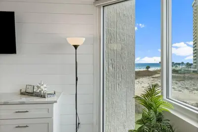 a floor lamp in a room with a view of the beach at Top of the Gulf 410 Beach Front Condo - Renovated! in Panama City Beach