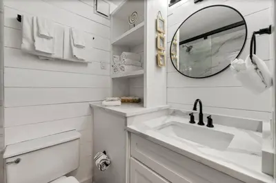 a white bathroom with a sink and a mirror at Top of the Gulf 410 Beach Front Condo - Renovated! in Panama City Beach