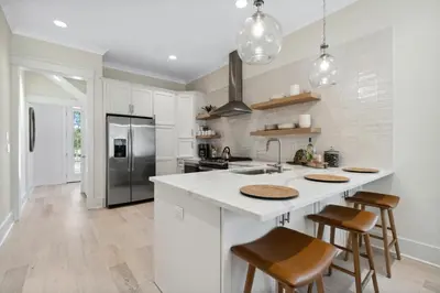 a kitchen with white cabinets and a kitchen island with bar stools at 30A Beach House - Harlie's House by Panhandle Getaways in Inlet Beach