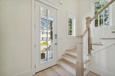 a white hallway with a staircase and windows at 30A Beach House - Harlie's House by Panhandle Getaways in Inlet Beach