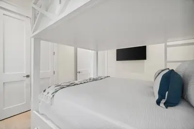 a white bedroom with a white bed with a tv at 30A Beach House - Harlie's House by Panhandle Getaways in Inlet Beach