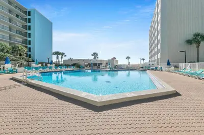 a large swimming pool with chairs and a building at Top of the Gulf 811 in Panama City Beach