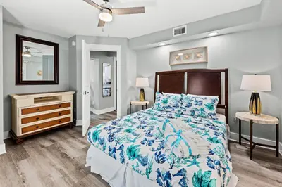 a bedroom with a bed and a dresser and a mirror at Welcome to Dolphin Fun A! BRAND NEW Duplex! Walk to the Beach! in Panama City Beach