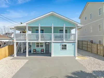 a blue house with a balcony on top of it at Welcome to Dolphin Fun A! BRAND NEW Duplex! Walk to the Beach! in Panama City Beach