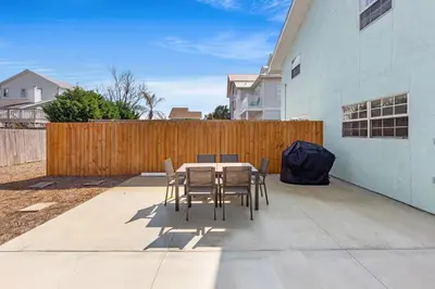 a patio with a table and chairs and a fence at Welcome to Dolphin Fun B, BRAND NEW Duplex Walk to the Beach in Panama City Beach