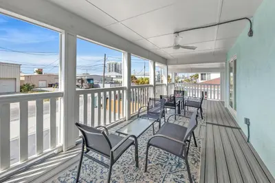 a balcony with chairs and tables and windows at Welcome to Dolphin Fun B, BRAND NEW Duplex Walk to the Beach in Panama City Beach