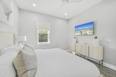 a white bedroom with a large bed and a tv at La Joya Azul in Inlet Beach