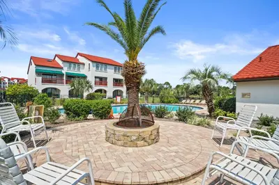 a patio with chairs and a palm tree in front of a building at St Thomas Square by Panhandle Getaways in Panama City Beach