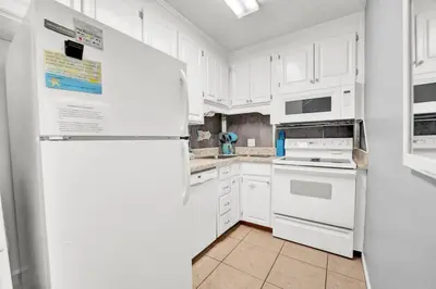 a kitchen with white appliances and white cabinets at 2 BR townhome w/private patio, beach access, 4 communal pools, hot tub, mini golf, tennis, & more! in Panama City Beach