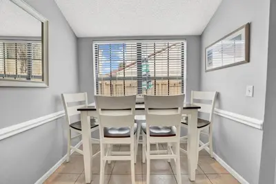 a dining room with a table and chairs and a window at 2 BR townhome w/private patio, beach access, 4 communal pools, hot tub, mini golf, tennis, & more! in Panama City Beach
