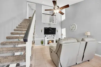 a living room with a ceiling fan and stairs at 2 BR townhome w/private patio, beach access, 4 communal pools, hot tub, mini golf, tennis, & more! in Panama City Beach