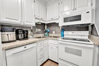 a white kitchen with white appliances and white cabinets at 2 BR townhome w/private patio, beach access, 4 communal pools, hot tub, mini golf, tennis, & more! in Panama City Beach