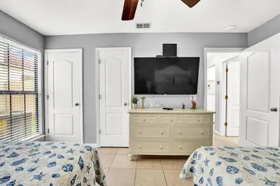 a bedroom with two beds and a flat screen tv at 2 BR townhome w/private patio, beach access, 4 communal pools, hot tub, mini golf, tennis, & more! in Panama City Beach