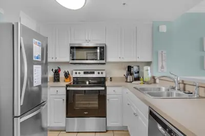 a kitchen with white cabinets and a stainless steel refrigerator at Majestic Beach Towers 1-1302 in Panama City Beach