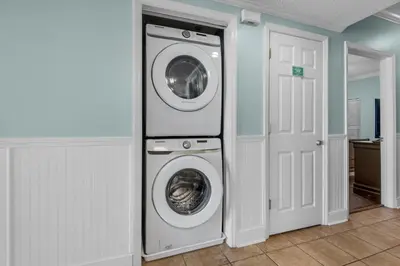 a laundry room with a washer and dryer next to a door at Majestic Beach Towers 1-1302 in Panama City Beach