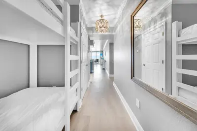 a white bedroom with a bed and a mirror at Emerald Beach 1036 - Turquoise Turtle in Panama City Beach