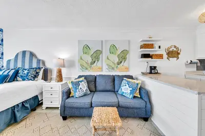 a bedroom with a blue couch and a bed at Top of the Gulf 808- Gulf Coast Getaway in Panama City Beach