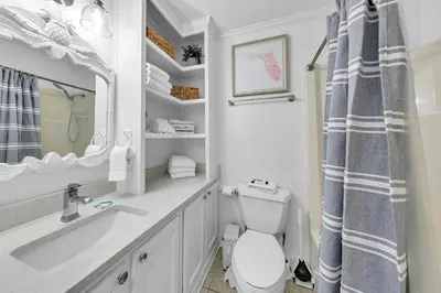 a bathroom with a toilet and a sink and a mirror at Top of the Gulf 808- Gulf Coast Getaway in Panama City Beach