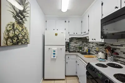 a kitchen with white cabinets and a refrigerator at Chic Townhouse Steps to the Beach Outdoor Pools in Panama City Beach