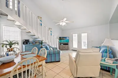 a living room with a staircase and a table and chairs at Chic Townhouse Steps to the Beach Outdoor Pools in Panama City Beach
