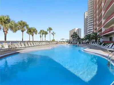 a large swimming pool with chairs and palm trees at Hidden Dunes 1803 in Panama City Beach