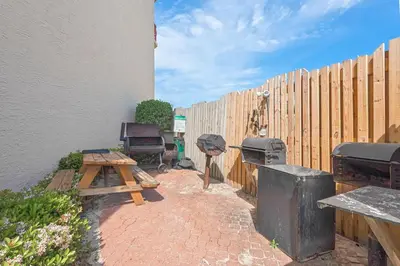 a backyard with a grill and a wooden fence at Hidden Dunes 1803 in Panama City Beach
