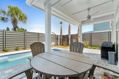 a wooden table and chairs on a patio with a swimming pool at Beach House with Private Pool - Elevated Escape by Panhandle Getaways in Panama City Beach