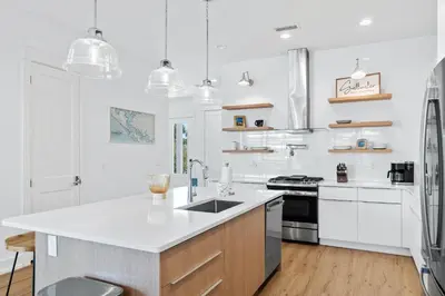 a white kitchen with a sink and a refrigerator at Beach House with Private Pool - Elevated Escape by Panhandle Getaways in Panama City Beach