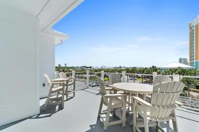a balcony with chairs and a table on a roof at Beach House with Private Pool - Elevated Escape by Panhandle Getaways in Panama City Beach