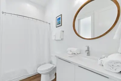 a white bathroom with a toilet and a mirror at Beach House with Private Pool - Elevated Escape by Panhandle Getaways in Panama City Beach