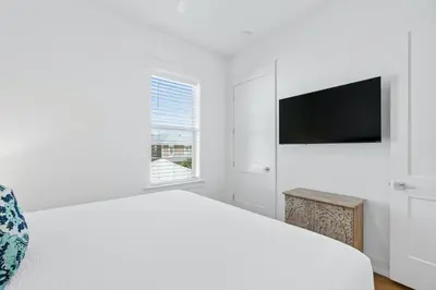 a white bedroom with a bed and a flat screen tv at Beach House with Private Pool - Elevated Escape by Panhandle Getaways in Panama City Beach