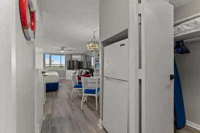 a kitchen and living room with white walls and a refrigerator at Top of The Gulf 306 in Panama City Beach