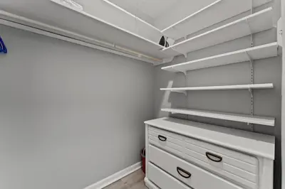 a walk in closet with white shelves and a drawer at Top of The Gulf 306 in Panama City Beach