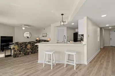 a kitchen and living room with a counter and stools at Aquavista 804E in Panama City Beach