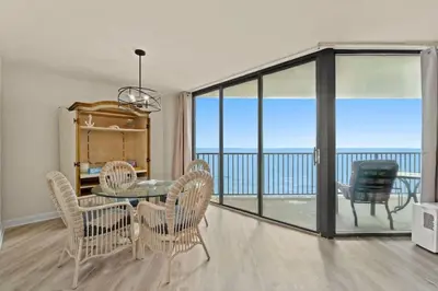 a dining room with a table and chairs and a balcony at Aquavista 804E in Panama City Beach