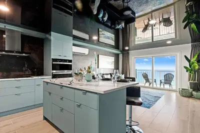 a kitchen with white cabinets and a view of the ocean at The Summit 1305 in Panama City Beach