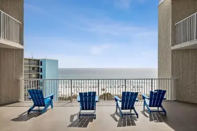 a balcony with blue chairs and a view of the ocean at Top Of The Gulf 704 in Panama City Beach
