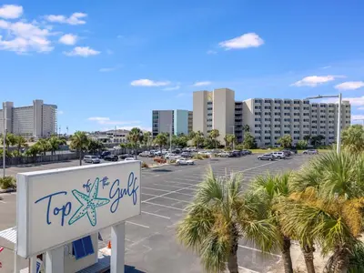 a sign in front of a parking lot with palm trees at Top Of The Gulf 704 in Panama City Beach