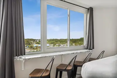 a bedroom with a bed and chairs and a window at Top Of The Gulf 704 in Panama City Beach