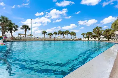 a swimming pool with palm trees and a blue sky at The Summit 817 in Panama City Beach