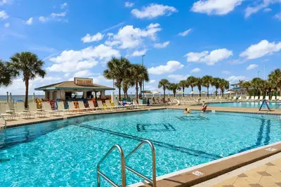 a large swimming pool with palm trees and a beach at The Summit 817 in Panama City Beach