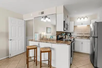 a kitchen with white cabinets and a stainless steel refrigerator at The Summit 1123 in Panama City Beach